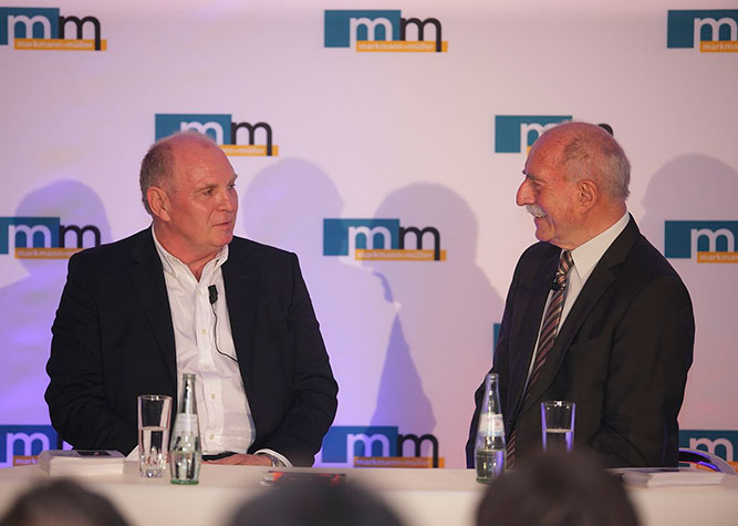 Uli Hoeneß, langjähriger Vorstand und Präsident des FC Bayern und Sportreporter Werner Hansch in einem Podiumsgespräch vor einer m+m Logowand.