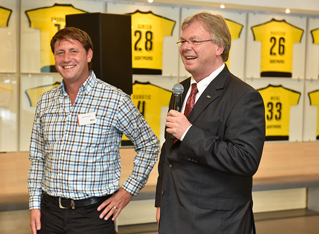 m+m Geschäftsführer Michael Müller und Zeljko Buvac vor einer BVB-Trikotwand.